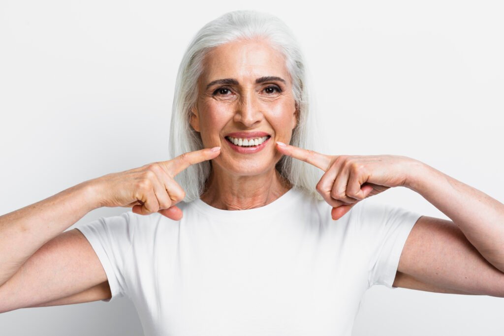 Happy senior woman pointing to her bright smile